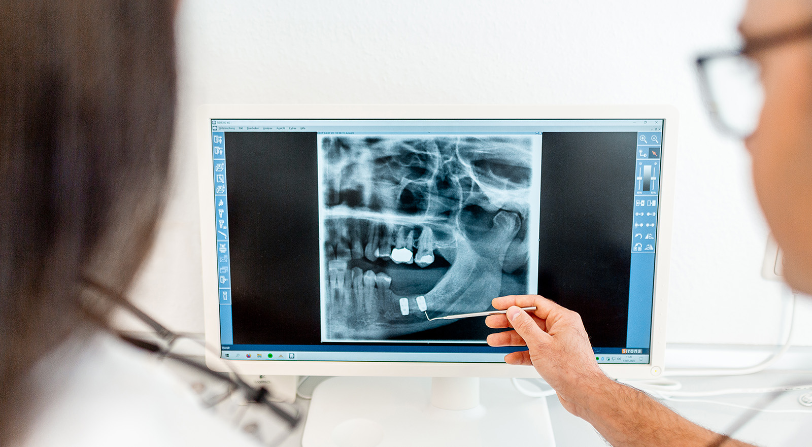 Zahnarzt Daniel Krutsch zeigt Patienten auf einem Röntgenbild, wie er die Zahnimplantate einsetzen will.