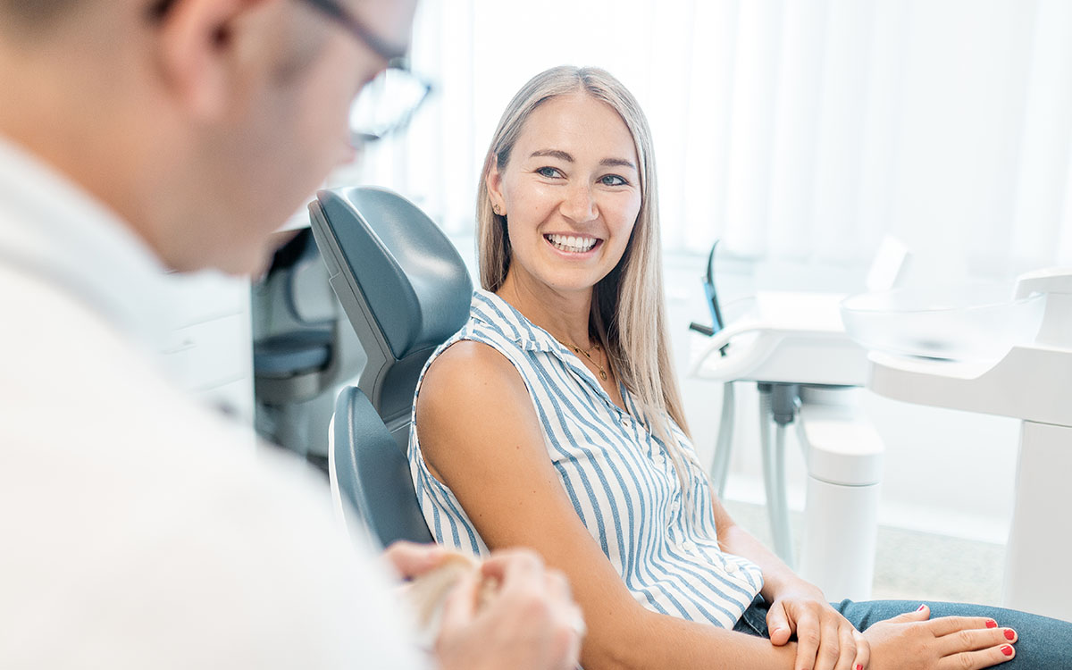 Patientin lächelt auf dem Stuhl von Zahnarzt Andreas Krutsch in Darmstadt.